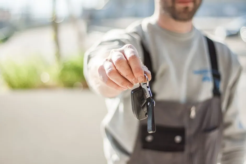 Driver holding a newly made replacement car key outdoors in Waxhaw NC